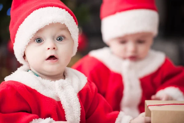 Noel ağacında hediyelerle Noel Baba gibi giyinmiş çocuklar.