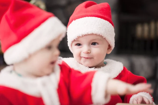Noel ağacında hediyelerle Noel Baba gibi giyinmiş çocuklar.