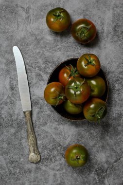 Siyah çakıl taşının içinde ve dışında sardalya domatesleri var.