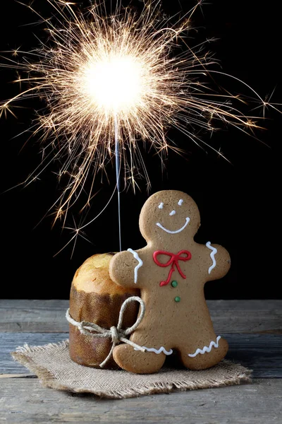 Noel 'de panettone ve zencefilli çörekçi hafif ahşap arka planda jüt kumaşa konur, Noel ışıltısı