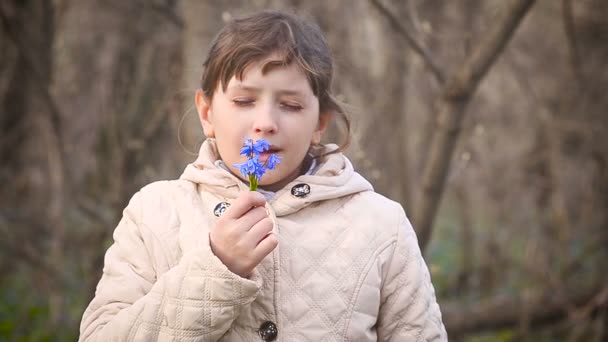 Mädchen schnüffelt an blauen Schneeglöckchen — Stockvideo