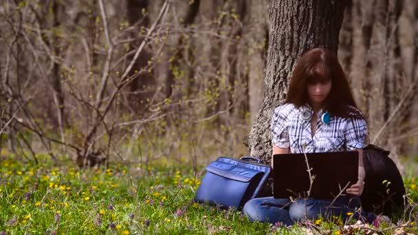 Una mujer que trabaja en una computadora en el bosque — Vídeo de stock