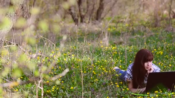 Femme se reposant sur un ordinateur portable couché sur la prairie — Video