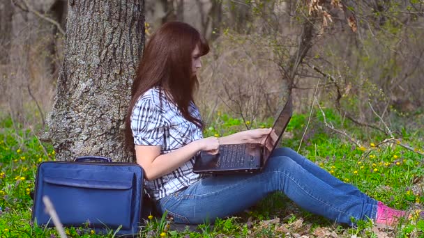 Девушка печатает на клавиатуре, сидя за ноутбуком — стоковое видео