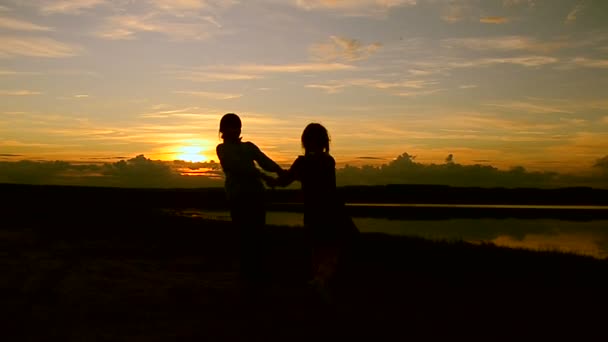 Meninas estão voltadas contra o belo pôr do sol ardente — Vídeo de Stock