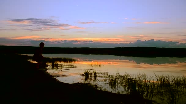 Дівчина грає у воді на заході сонця — стокове відео