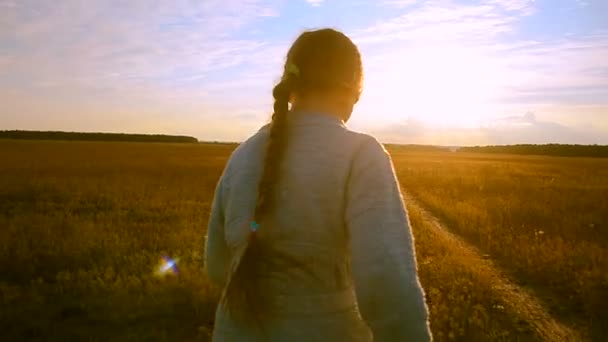 Menina corre ao pôr do sol ao longo da estrada e olhando para trás rindo — Vídeo de Stock