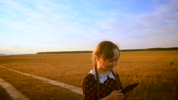 Mädchen auf dem Hintergrund des Sonnenuntergangs mit dem Tablet — Stockvideo