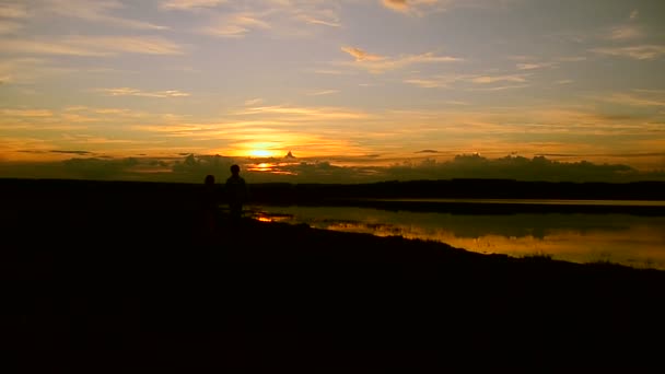 Flickor löper längs stranden vid solnedgången bakgrund — Stockvideo