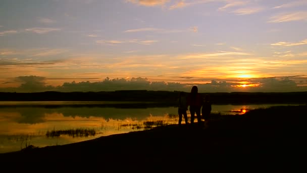 Kinderen met moeder lopen op het strand bij zonsondergang — Stockvideo