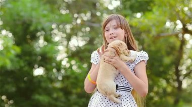 Kız bir köpek yavrusu üzerinde ellerini tutar.
