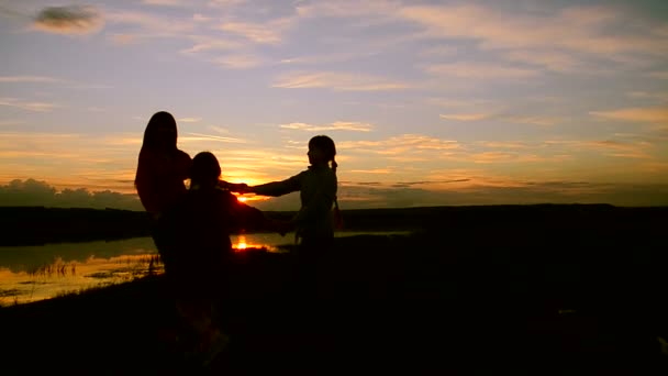 Niños con madre giran en la orilla al atardecer — Vídeos de Stock