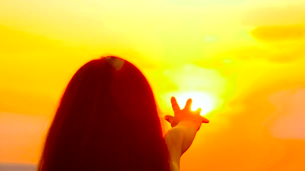 Дівчина тягне руку до золотого сонця — стокове відео
