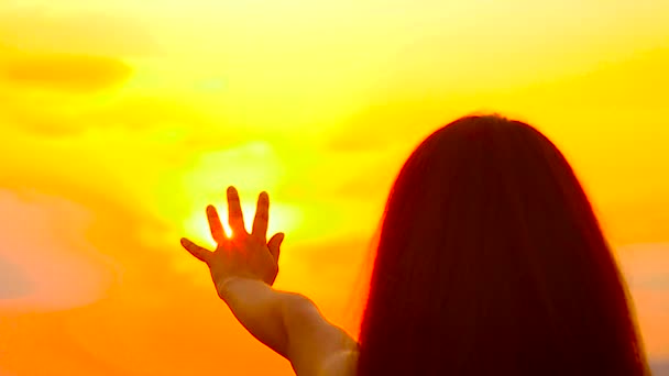 Девушка тянет руку к золотому солнцу — стоковое видео