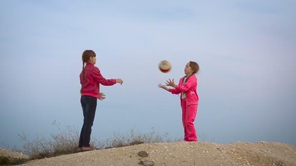 Ragazze che giocano a palla contro il cielo — Video Stock