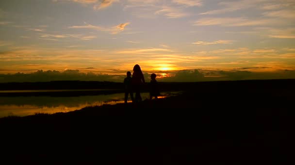 Τα παιδιά με τη μαμά με τα πόδια στην παραλία το ηλιοβασίλεμα — Αρχείο Βίντεο
