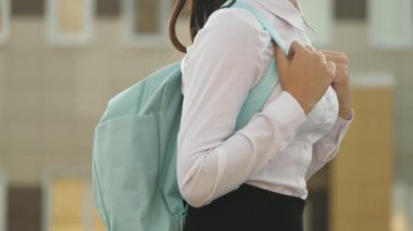 Eğitim konsepti. Genç bir kız aceleyle sınıfa gidiyor. Sırt çantalı bir liseli kız okula gidiyor. Güzel bir genç öğrenci sınıfa gidiyor..