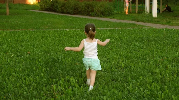 Glückliches Kind läuft im Sommer auf einer Wiese auf einem grünen Gras. fröhliches kleines Mädchen rennt über das Feld. Glückskonzept. Kinder spielen im Sommer auf dem Rasen. Zeitlupe. Baby spielt im Frühling im Park. — Stockfoto