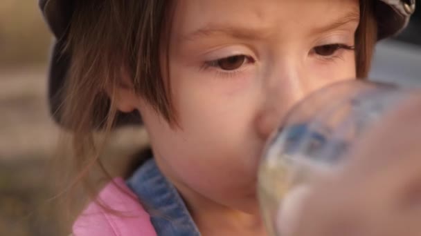 Un bambino piccolo beve acqua pulita da una bottiglia per la salute. La ragazza si disseta. Un ragazzino al parco. Primo piano — Video Stock