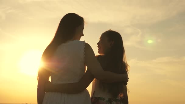 Família feliz mãe e filha em um campo ao pôr do sol. Mamãe abraços filha, eles admiram belo pôr do sol. conceito de família feliz de crianças e crianças. mãe e bebê caminham no parque, campo, ao sol — Vídeo de Stock