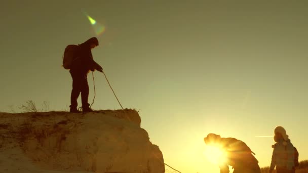 Klimmers-reizigers beklimmen de berg met touw. gezamenlijk werk van toeristen. vreugdevolle toeristen springen en zwaaien met hun handen. teamwork van zakenmensen. reizigers mannen en vrouwen helpen elkaar. — Stockvideo