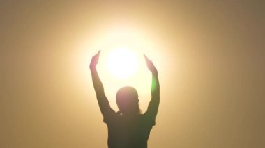Özgür kız güneşi elinde tutuyor. Barış, ışık, sıcaklık kavramı. Çocuk oynuyor, güneş ışığını elleriyle yakalıyor. Barış, sevgi, nezaket kavramı. Güneş yıldızının avuçlarında bir gencin silueti.