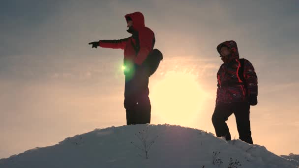 I turisti salgono sulla cima di una collina innevata. escursioni in inverno. I viaggiatori su una montagna innevata sono guidati dal terreno e scelgono la direzione del viaggio. lavoro di squadra di uomini d'affari. — Video Stock