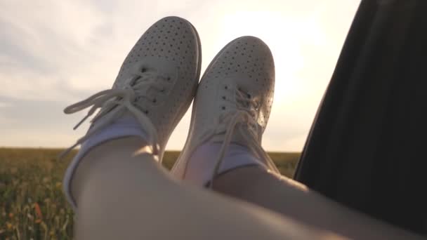 Free woman travels by car. healthy Young woman enjoys traveling by car, protruding her legs from an open window. Legs of a girl in car window, riding car on country road past wheat field.travel — Stock Video