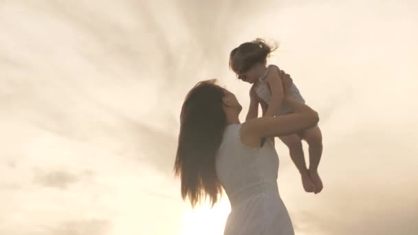 La mamma gioca con il suo bambino al tramonto. madre getta la sua amata figlia sana in cielo tra le sue braccia. madre felice e piccolo bambino sano si stanno abbracciando nel parco al sole. famiglia in vacanza. — Video Stock