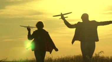 Kızlar pilot olmayı hayal eder, gün batımında oyuncak bir uçakla oynamayı. Çocuklar uçakla güneşte tarlayı geçerler. Uçma hayalleri. Mutlu çocukluk. Uçakta oynayan çocukların silueti. seyahat
