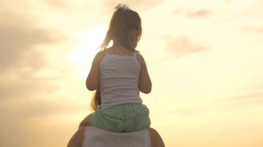 Küçük şirin bebek annesinin omuzlarında yuvarlanıyor. Kız, annenin boynuna oturur. Tasasız anne ve kızı parkta yürüyorlar. Dışarıda mutlu, sağlıklı bir aile. Mutlu anne ve bebek.