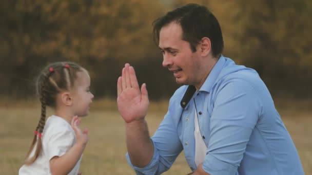 Ayah memainkan tangannya dengan putri kecilnya. Ayah dan anak tercinta bersenang-senang bersama. Konsep keluarga bahagia. Kerja sama tim. Anak itu dan pria itu bersenang-senang di taman. Berjalan di luar ruangan di alam — Stok Video