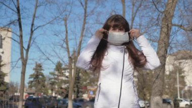 Sağlıklı, koruyucu tıp maskeli bir kız, parmaklarını iyi gösteriyor. Özgür kadın virüsler için tıbbi maske takıyor ve klas gösteriyor. Pandemik koronavirüs için sağlık ve güvenlik kavramı