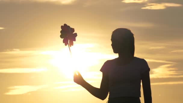 Silueta fată joc pinwheel parc în mișcare lentă. Copilul care se joacă în parc prinde vântul. Copil fericit joc cu pinwheel distractiv. Fericire vacanță copilărie copii fericit vacanță de familie. copilărie — Videoclip de stoc