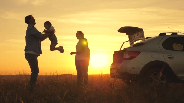 Baba oynar ve neşeli kızını gökyüzüne fırlatır, anne ve çocuklar gün batımında dans eder. Ebeveynler ve çocuklar arabayla mola vermek için durdular. Mutlu aile arabayla seyahat eder. Araba yolculuğu konsepti. sağlıklı aile — Stok video