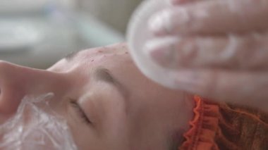 Kozmetik uzmanları tıbbi eldivenlerle bir kadının yüzüne iğne yapar. Güzellik Kliniği. Kadın kozmetik yüz bakımı yaptırıyor. Botoks kolajen enjeksiyonları. gençlik ve güzellik kavramı