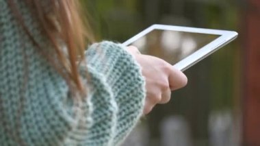 Şehrin kaldırımında yürüyen bir kadın tablet bilgisayarla çalışıyor. Yakın plan. Şehir caddesinde dijital tablet kullanan bir kız. Öğrenci kızların elleri tabletlere dokunuyor..