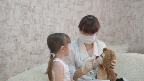 Dětský a ženský dětský lékař si hrají s medvídkem. Pediatr s maskou si hraje s malou holčičkou v nemocnici. Ten kluk si hraje v nemocnici. Hra předstírá, že je doktor, zdravotní sestra, léčí pacienta.
