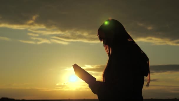 Kobieta czyta książkę w promieniach słońca. Człowiek czyta Biblię na zewnątrz. Człowiek trzyma Biblię w rękach i studiuje Słowo Boże o wschodzie słońca na szczycie góry. Szukanie prawdy w Piśmie Świętym. — Wideo stockowe