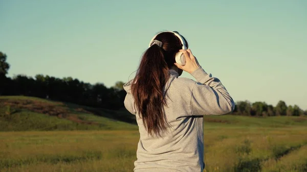 Trainingsjogging. Freie junge Frau läuft im Sommer im Park im Morgengrauen und hört Musik mit Kopfhörern. Gesunde schöne Mädchen beschäftigt sich mit Fitness, Joggen auf dem Land. Joggerin atmet frische Luft — Stockfoto