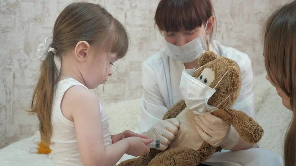 Orvosososososososososososososososat játszó gyerekek, oltás. A kisgyermek a játékállatokat injekciókkal kezeli. A kislány anyával játszik a kórházban. Egészséges lány és játékmackó. A gyerek kórházban játszik.. — Stock Fotó