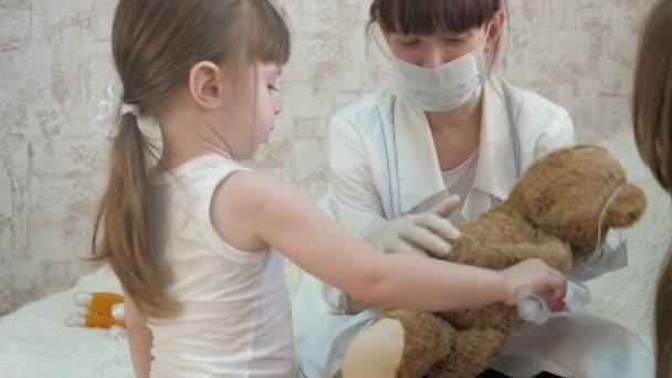 Barn leker läkare, sjuksköterska, behandla med vaccin. Små barn behandlar leksaksdjur med injektioner. En liten flicka leker med mamma på sjukhuset. Friska flicka och leksak björn. Barnlekar på sjukhus. — Stockvideo