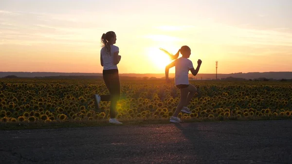 Aufwärmen für Sportmädchen. Abendliches Lauftraining. Sportliche Teenager laufen im gleißenden Sonnenuntergang die Straße entlang. Gesundes Joggen und Outdoor-Bewegungskonzept. Mädchen joggen. Freiheit, Leben in Bewegung, Gesundheit. — Stockfoto