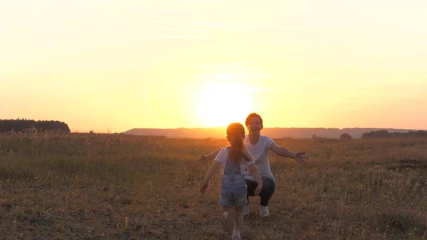 Gelukkige kleine dochter rent naar mama, kind en moeder knuffelen in de zon. Mama en baby knuffel. Gelukkige familie, moeder en dochter in het veld spelen in de zon. concept van gelukkig gezin en gezonde kinderen. baby houdt van mama — Stockfoto