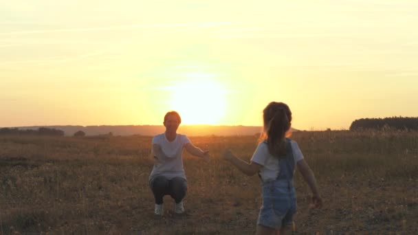 Mama i dziecko przytulają się w parku o zachodzie słońca. Mała córeczka biegnie do mamy, dziecka i matki przytulić się w słońcu. Matka i córka bawią się w słońcu. Szczęśliwa rodzina, zdrowe dzieci. Dziecko kocha mamusię — Wideo stockowe