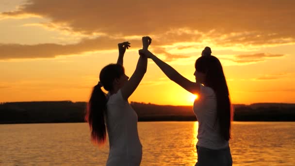 Sağlıklı gençler sevinçle ellerini kaldırır. Kıyıda eğlenceli bir tatil. Yaz gününü bir plaj partisiyle kutlarız. Özgür kızlar bir yaz akşamı gün batımında neşeyle dans ederler. Açık hava kutlaması — Stok video