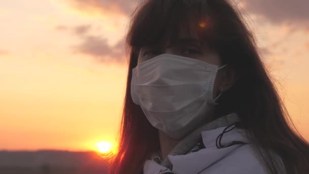 Pandemisch coronavirus COVID-19. Vrije vrouw met een beschermend medisch masker bij zonsondergang. Bescherming tegen virussen en bacteriën. gezondheids- en veiligheidsconcept, coronavirus N1H1, virusbescherming. — Stockvideo