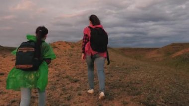 Özgür kadınlar dağa tırmanır, el ele tutuşur zaferlerine doğru yürürler. Gezginlerin ortak çalışması. Macera ve seyahat. Turist kızlar sırt çantalarıyla renkli yağmurluklarla seyahat ederler. Yürüyüş