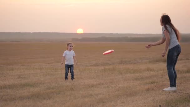 Happy family mom and child play on field throw a flying disc in park. Mom and happy baby throw a flying toy to each other. Mother and little healthy daughter have fun together. Cheerful kid rejoices. — Video Stock