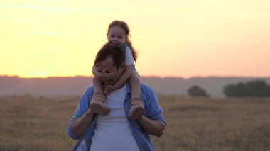 Çocuk babasının boynuna oturur ve sevgili babasına sarılır. Şirin bebek babamla oynuyor. Omuzlarında bebek olan mutlu bir aile babası. Parkta kızıyla birlikte tasasız bir ebeveyn. Mutlu aile